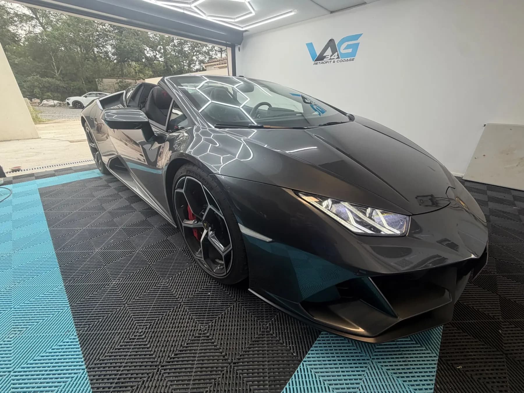 L’atelier VAG34 : une Lamborghini Huracán Evo Spyder devant le logo de l’atelier