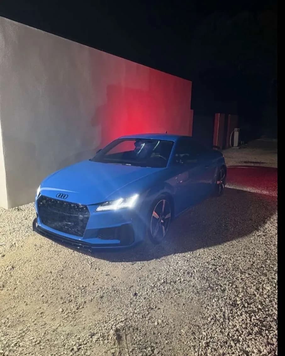Audi TT bleue de nuit devant l’atelier VAG34, phares allumés